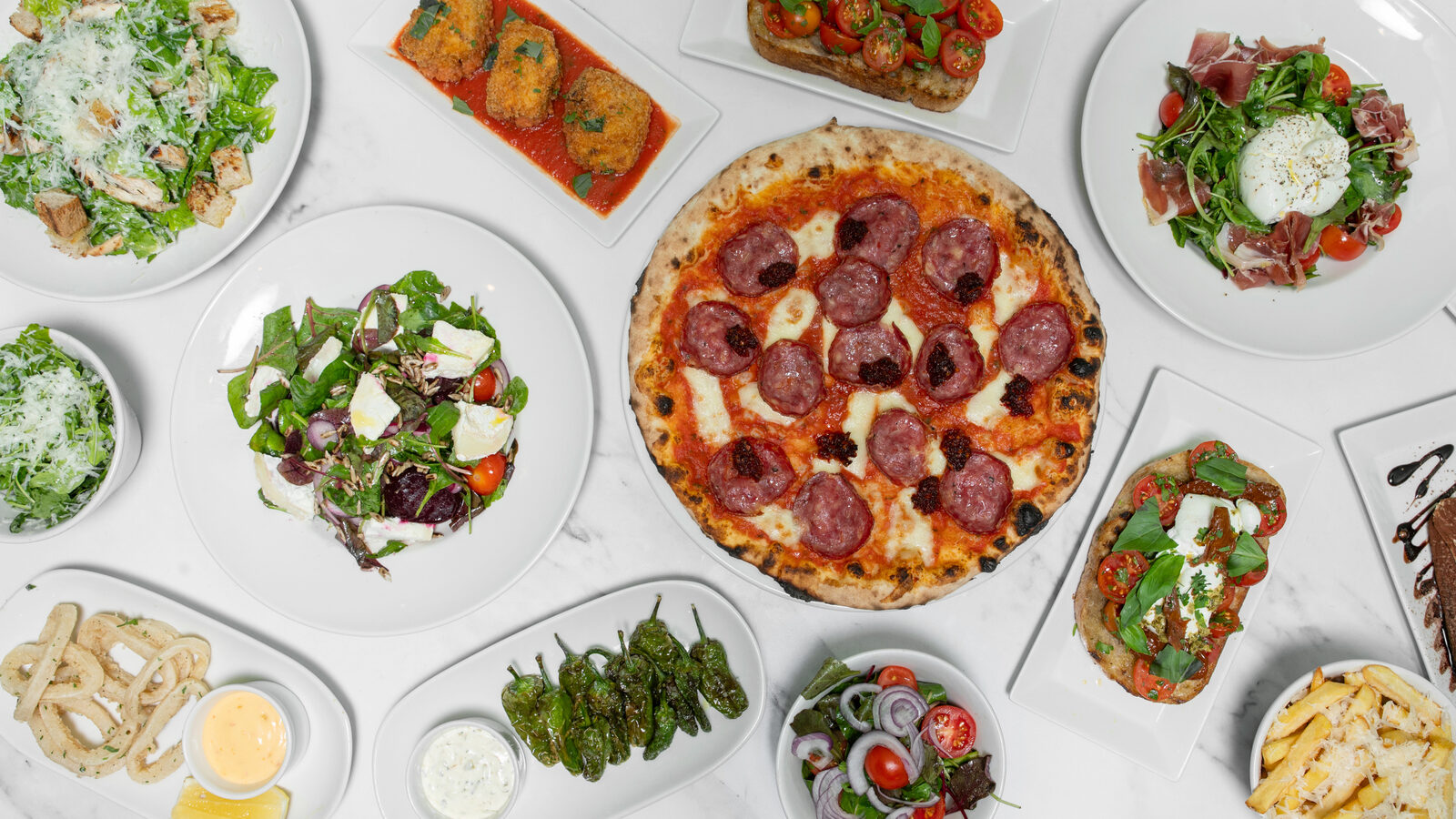 Spread of Yellowstone pizzas, salads and starters on a marble table